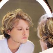 A generic photo of a young man staring at himself in the mirror