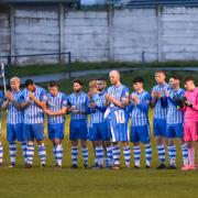 Winsford United's players carry the shirt of teammate Ross Aikenhead during a minute's applause in his memory