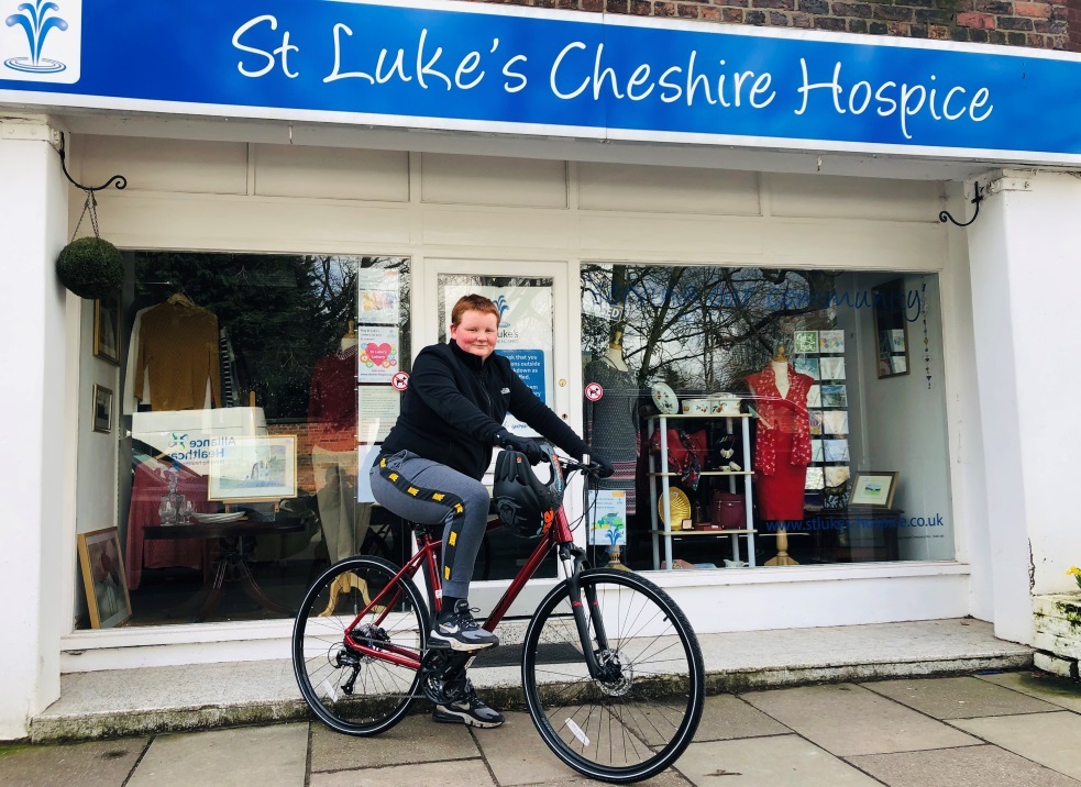 Matty cycles past St Lukes Hospice charity shop in Hartford
