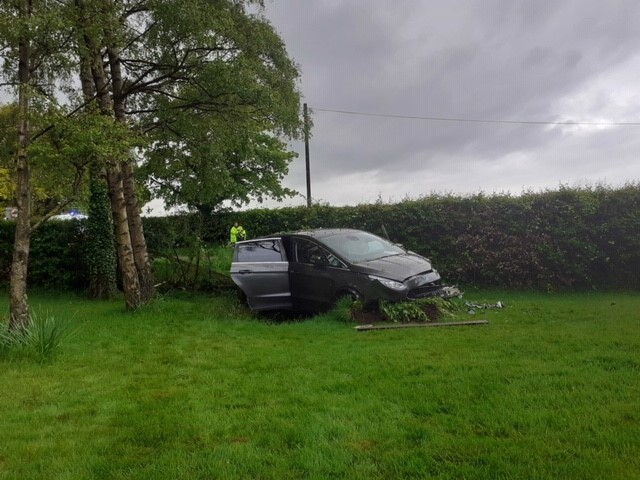 Another image of a car that has gone through the hedge in to the garden