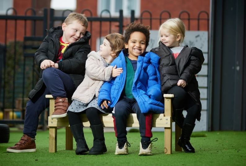 Children having fun on a buddy bench donated by Barratt Homes