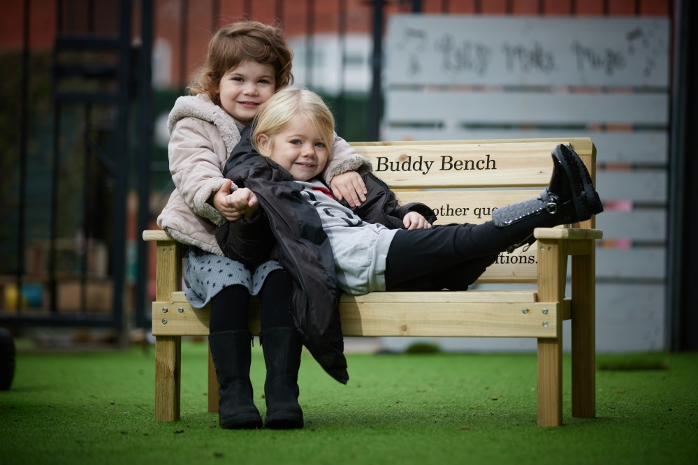 Children having fun on a buddy bench donated by Barratt Homes