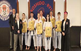 Karate students who passed their gradings, pictured with coaches and grading panel member
